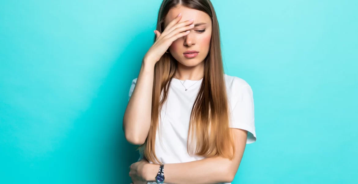 exhausted-woman-touching-head-while-standing-with-closed-eyes