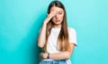 exhausted-woman-touching-head-while-standing-with-closed-eyes