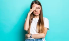 exhausted-woman-touching-head-while-standing-with-closed-eyes